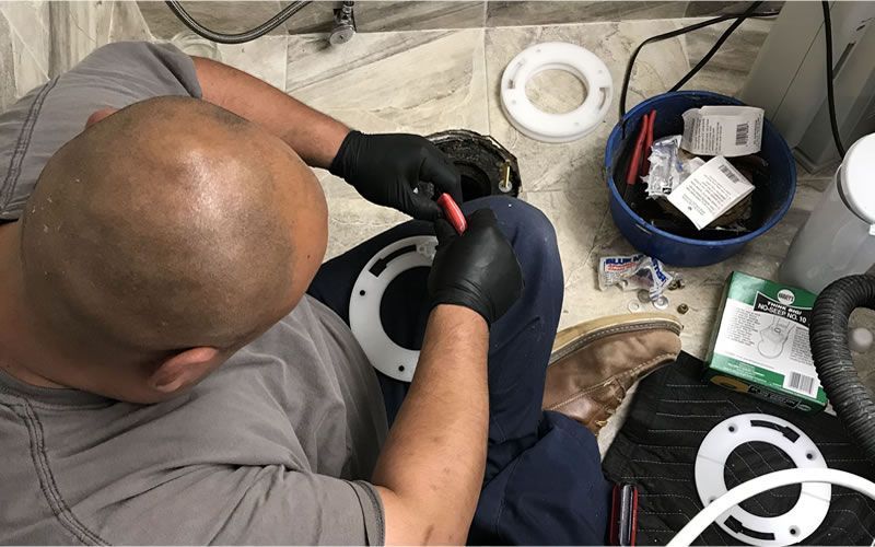 a man is working on a toilet with a box of plumbers tools on the floor