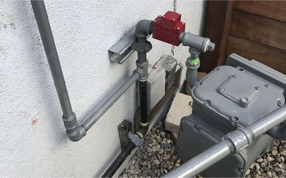 a gas meter is connected to a gray pipe