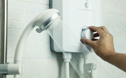 a person is adjusting the temperature of a shower head in a bathroom .