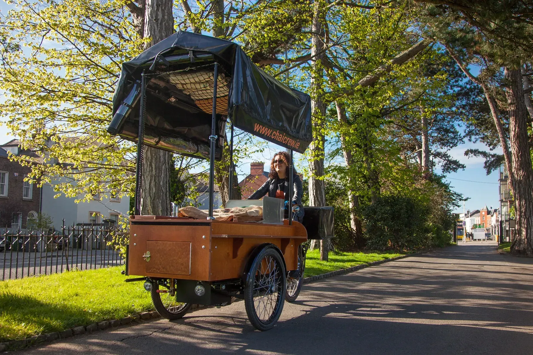 A woman is riding a bicycle with a cart attached to it.