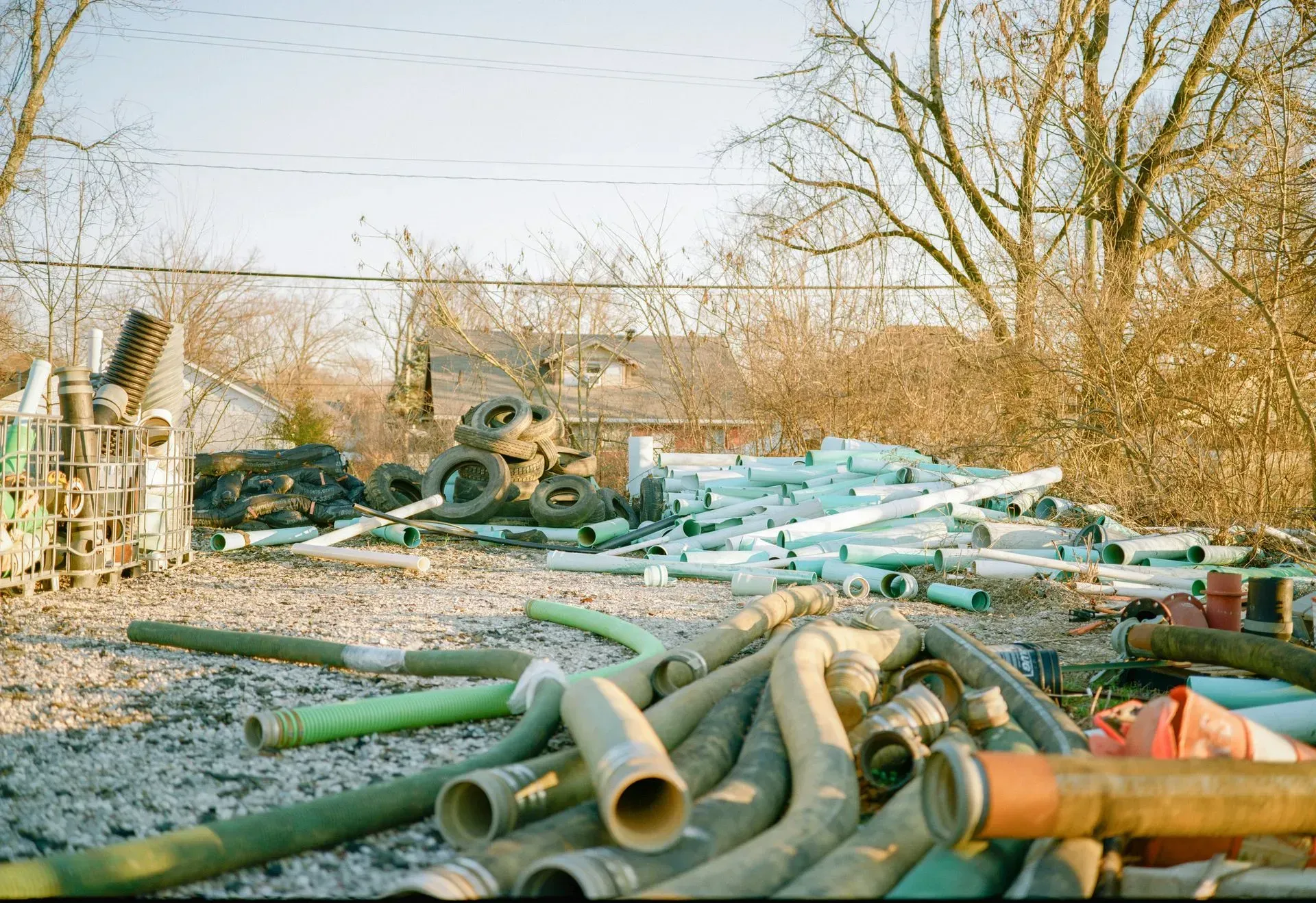 Scattered construction debris, old tires, and PVC pipes in a yard.