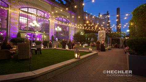 A group of people are sitting outside of a building with purple lights hanging from the ceiling.