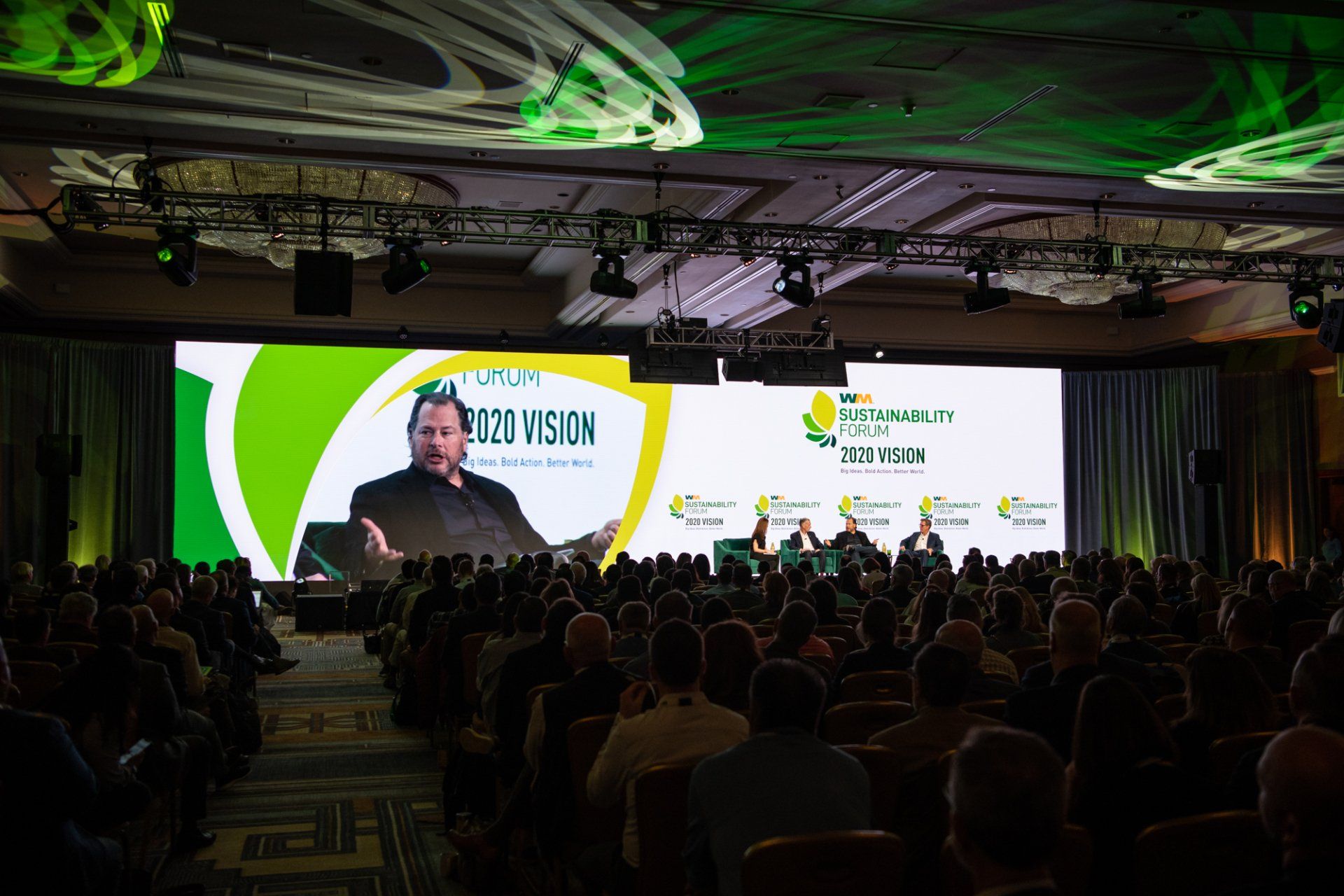 A large group of people are sitting in front of a large screen.