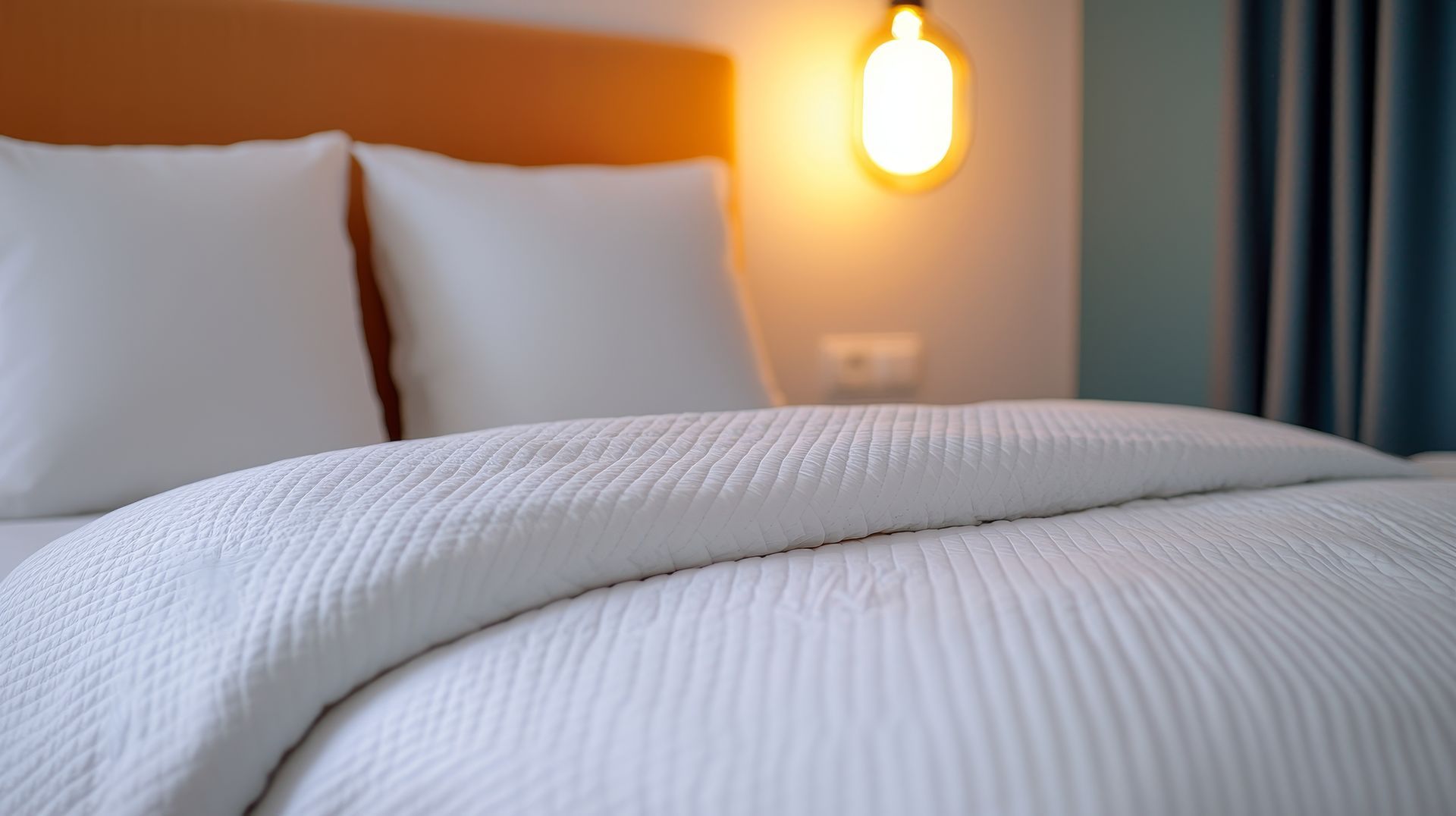 A bed with white sheets and pillows in a hotel room.
