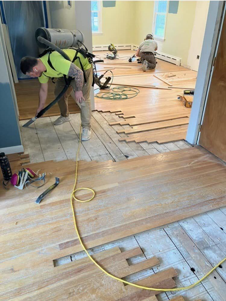 A man is using a vacuum cleaner to clean a wooden floor.