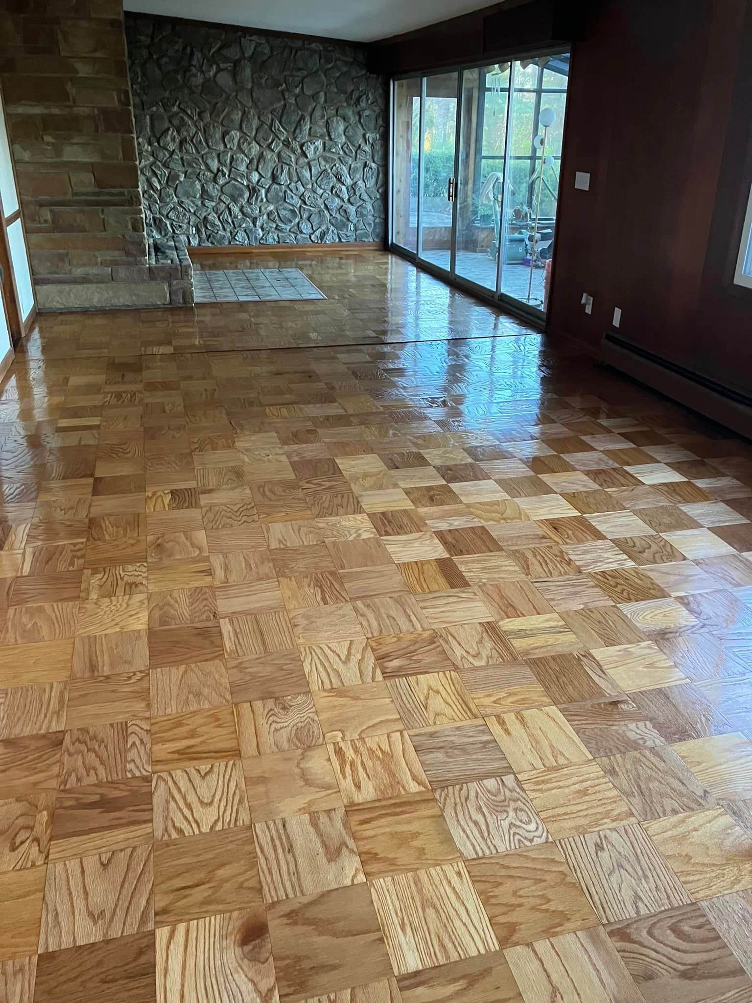 A living room with a wooden floor and a stone wall.