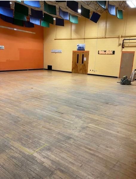 A large empty room with wooden floors and orange walls.