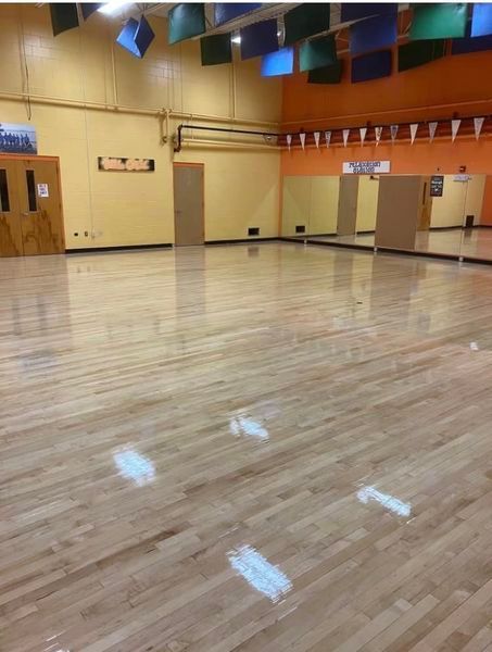 A large empty dance studio with a wooden floor and mirrors.