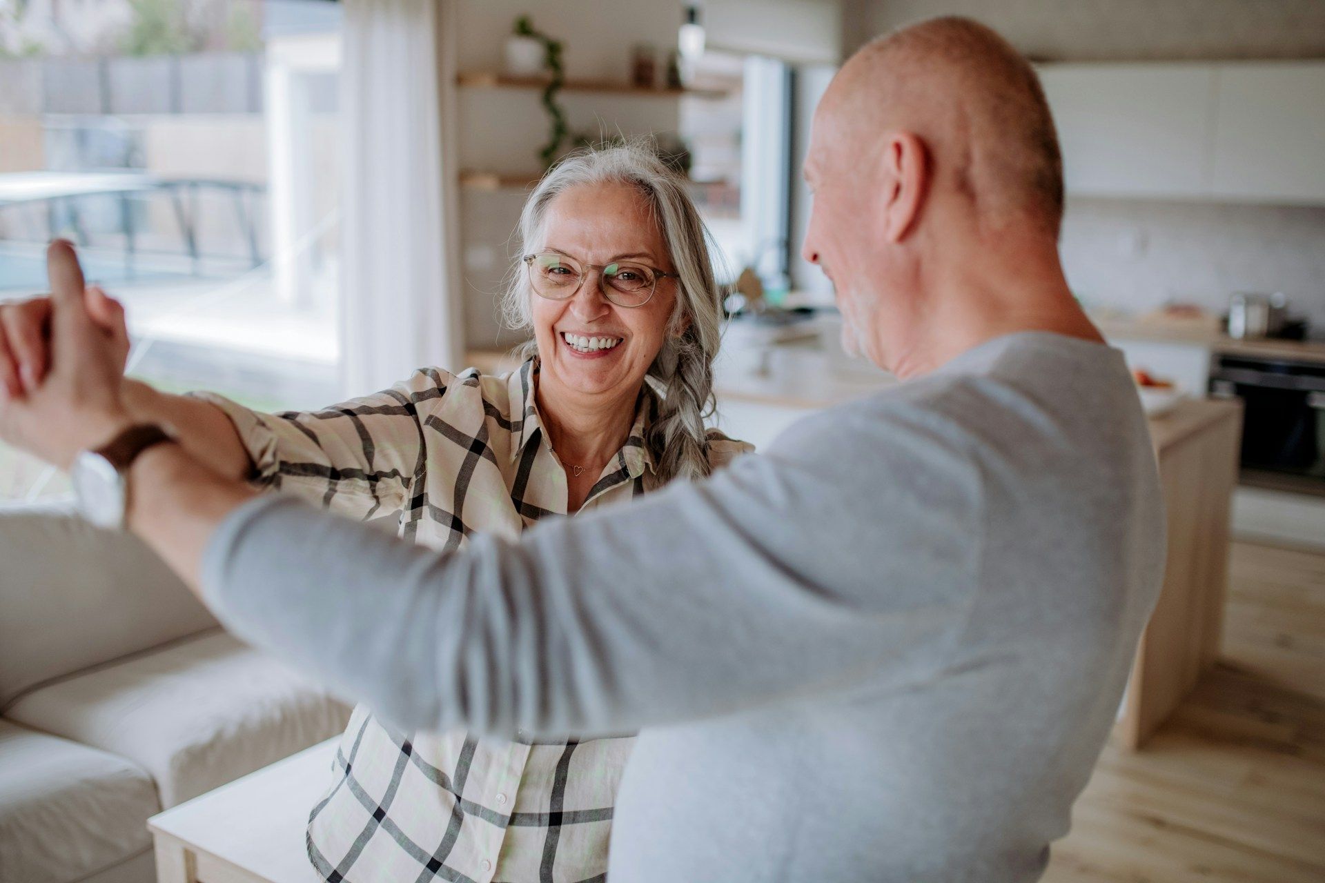 Two people smiling and dancing in a bright living room