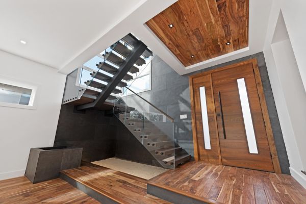 A modern staircase with a glass railing and a wooden door