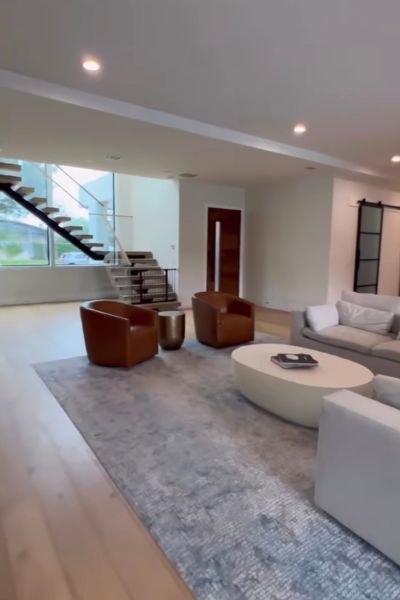 A living room with furniture and a staircase in the background