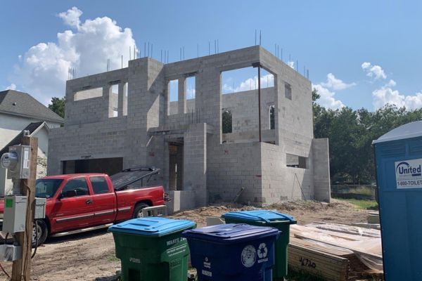 A red truck is parked in front of a building under construction.