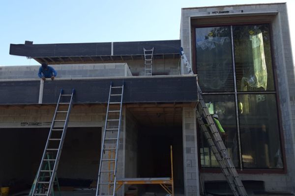 A man is sitting on the roof of a building under construction.