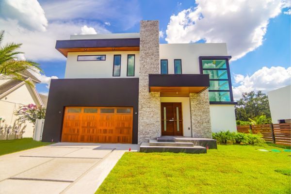 A modern house with a wooden garage door and a lush green lawn.