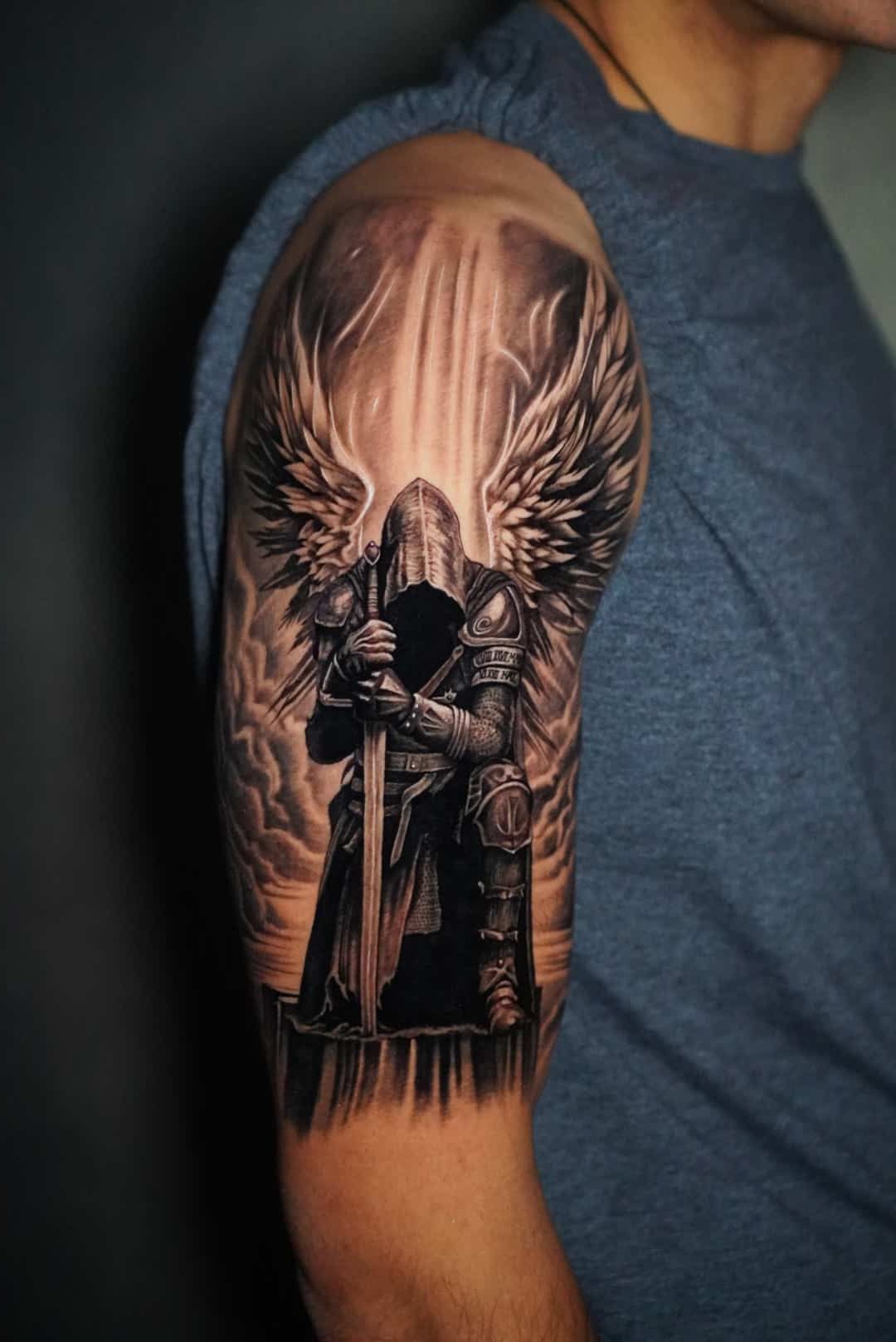 Arm tattoo: Knight with wings and sword in detailed grayscale.