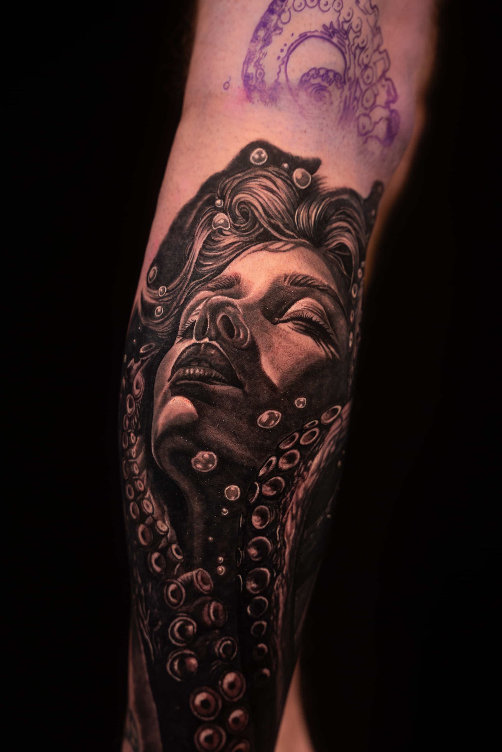 Black and gray tattoo of a woman's face surrounded by octopus tentacles. Bubbles and delicate shading add depth.