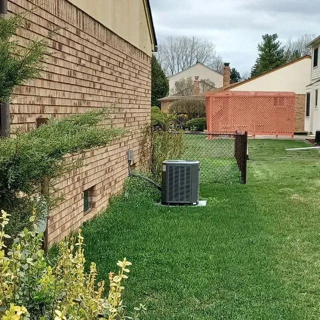 A large air conditioner is sitting in front of a brick building.