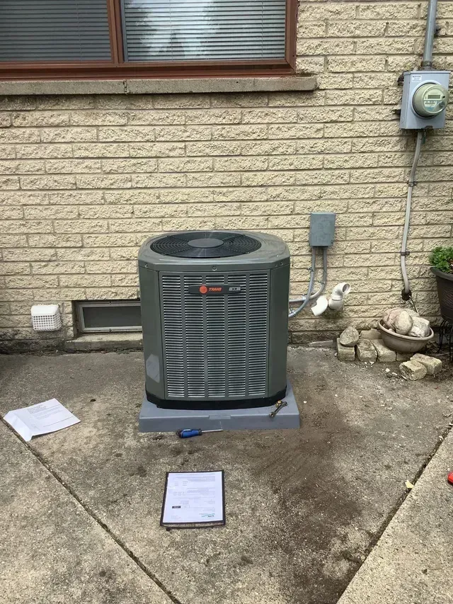 An air conditioner is sitting on the side of a brick building.