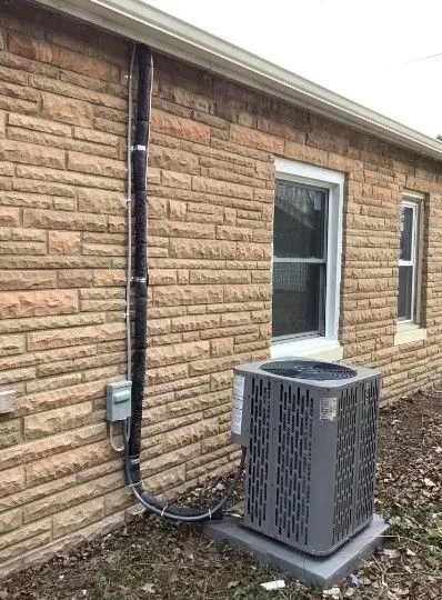 A brick house with a air conditioner on the side of it.