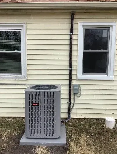 An air conditioner is sitting on the side of a house next to a window.