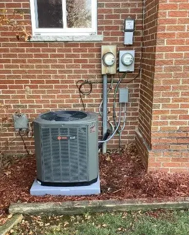 An air conditioner is sitting on the side of a brick building.