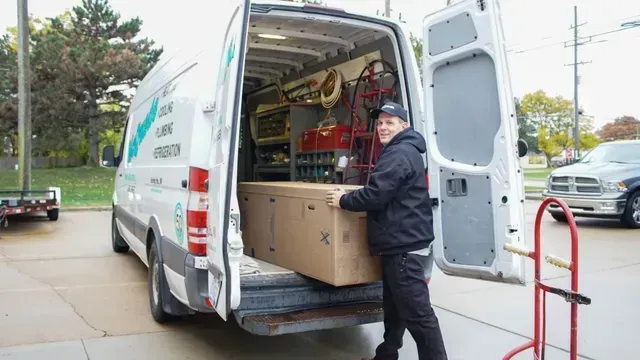 A man is loading a box into the back of a van.