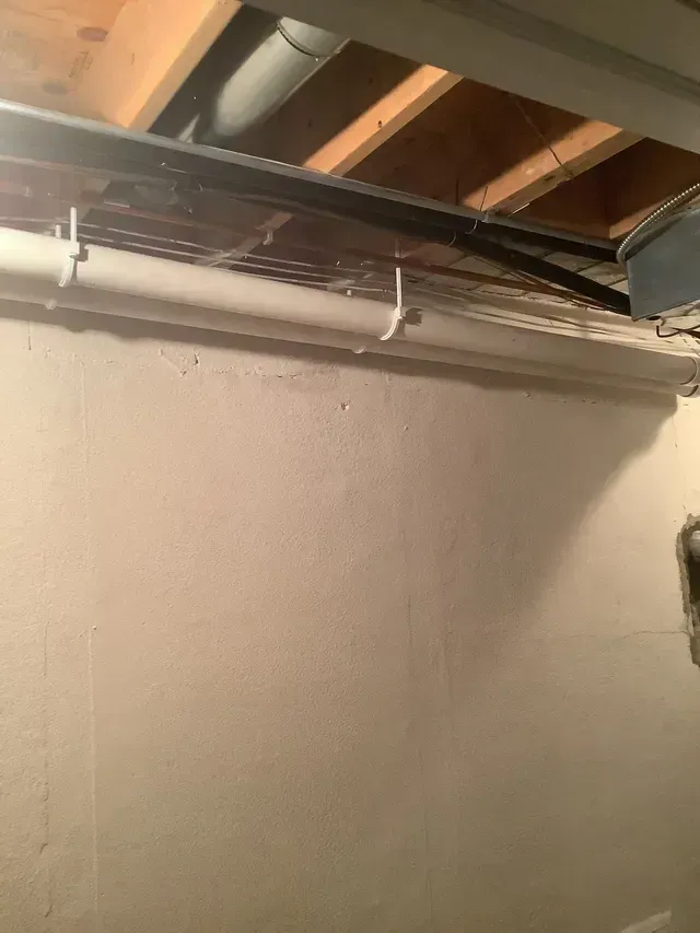 A white pipe is hanging from the ceiling of a room.
