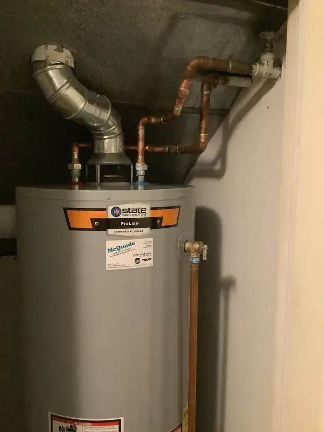 A water heater is sitting in a room next to a wall.
