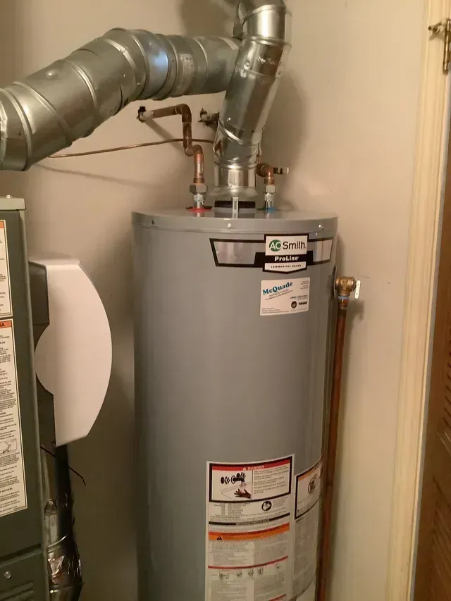 A water heater is sitting in a room next to a furnace.