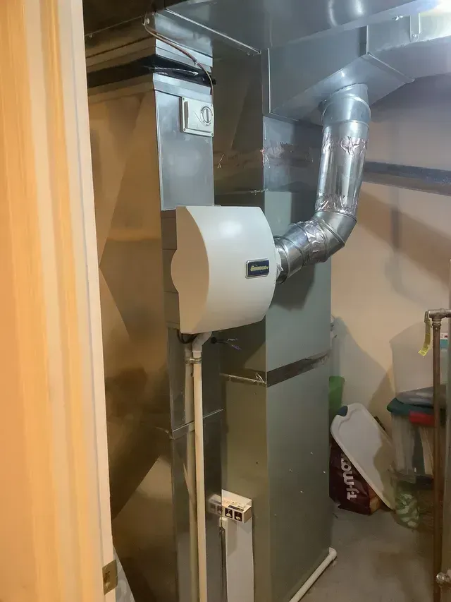 A stainless steel air conditioner is sitting in a room next to a door.