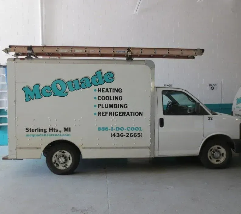 A white mcquade truck is parked in a garage