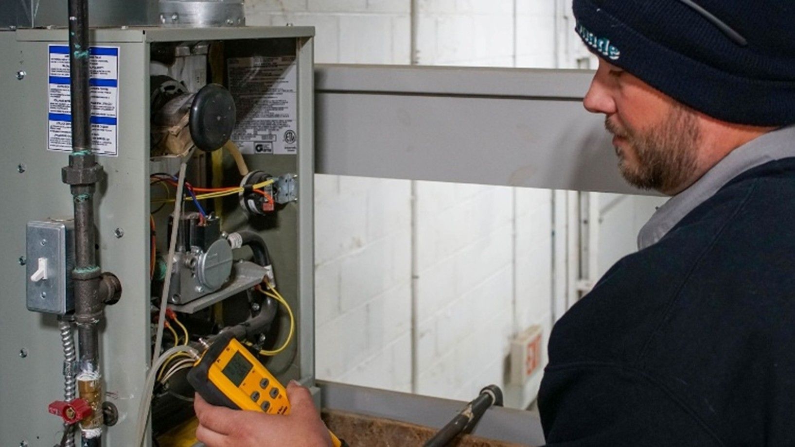 A technician performing maintenance on an indoor boiler system.]