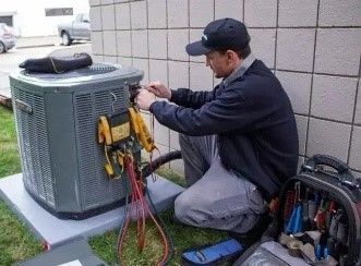 Technician working on an HVAC unit with tools and gauges.