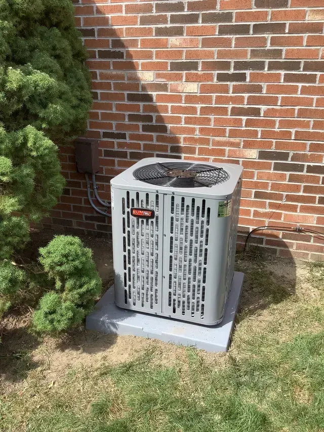 Outdoor air conditioning unit on a concrete slab next to a brick wall. Outdoor air conditioning unit on a concrete slab next to a brick wall.
