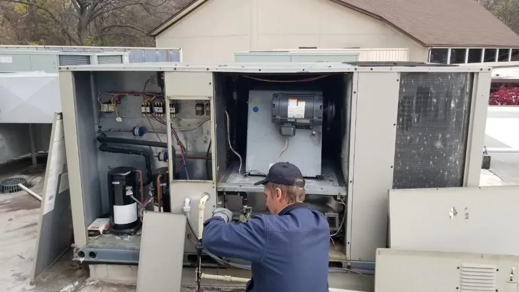 A man is working on an air conditioner outside of a building.