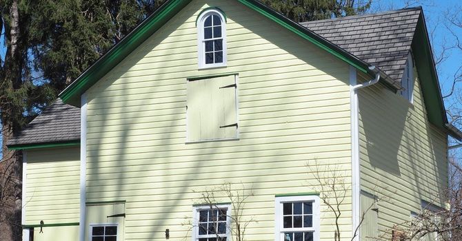 A house with a brick chimney and vinyl siding. Image is focused on the house's gutter.