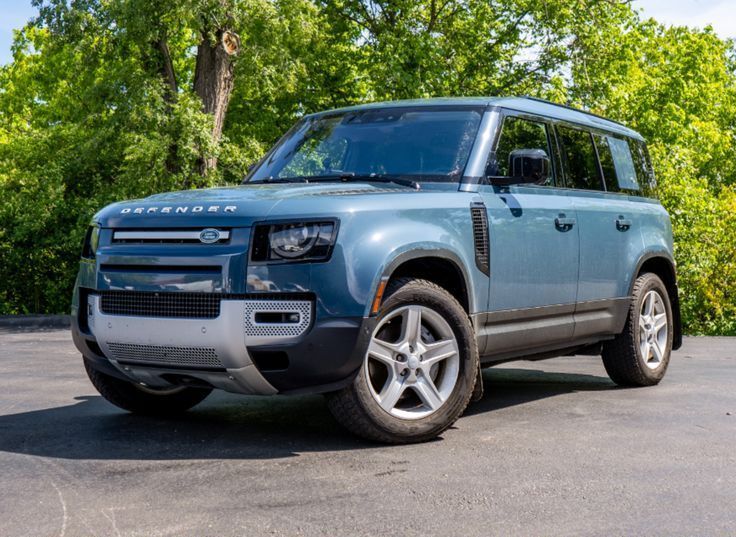 A blue land rover defender is parked in a parking lot.