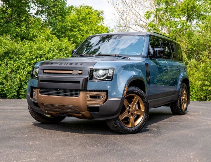 A blue land rover defender is parked on the side of a road.
