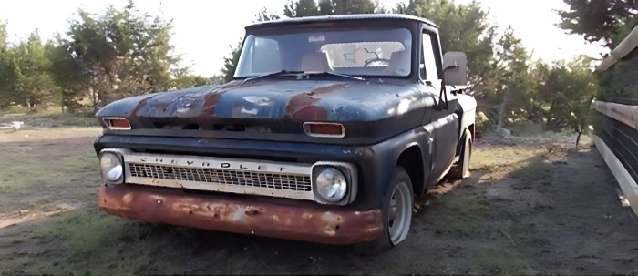 An old rusty pickup truck is parked in a grassy field.