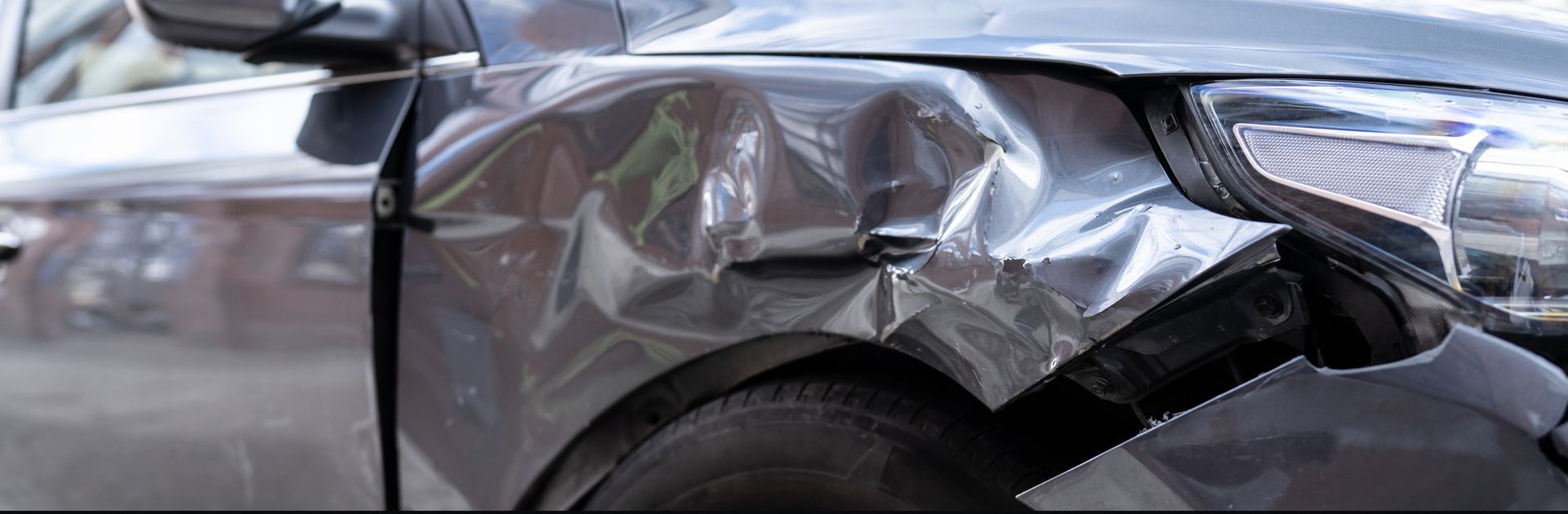 A close up of a car with a damaged fender wrapped in plastic.