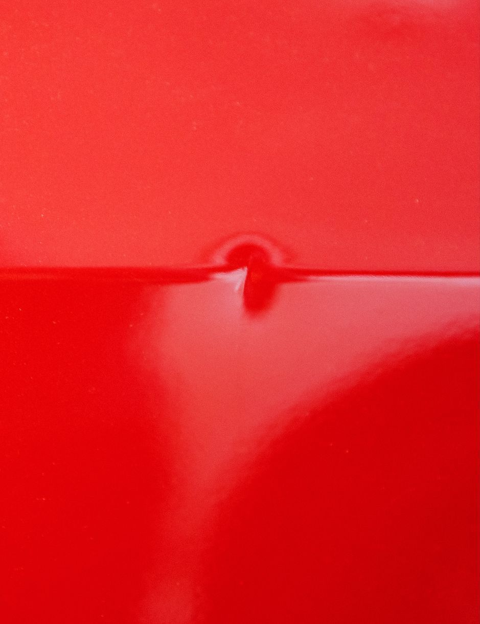 A close up of a red car with a hole in it.