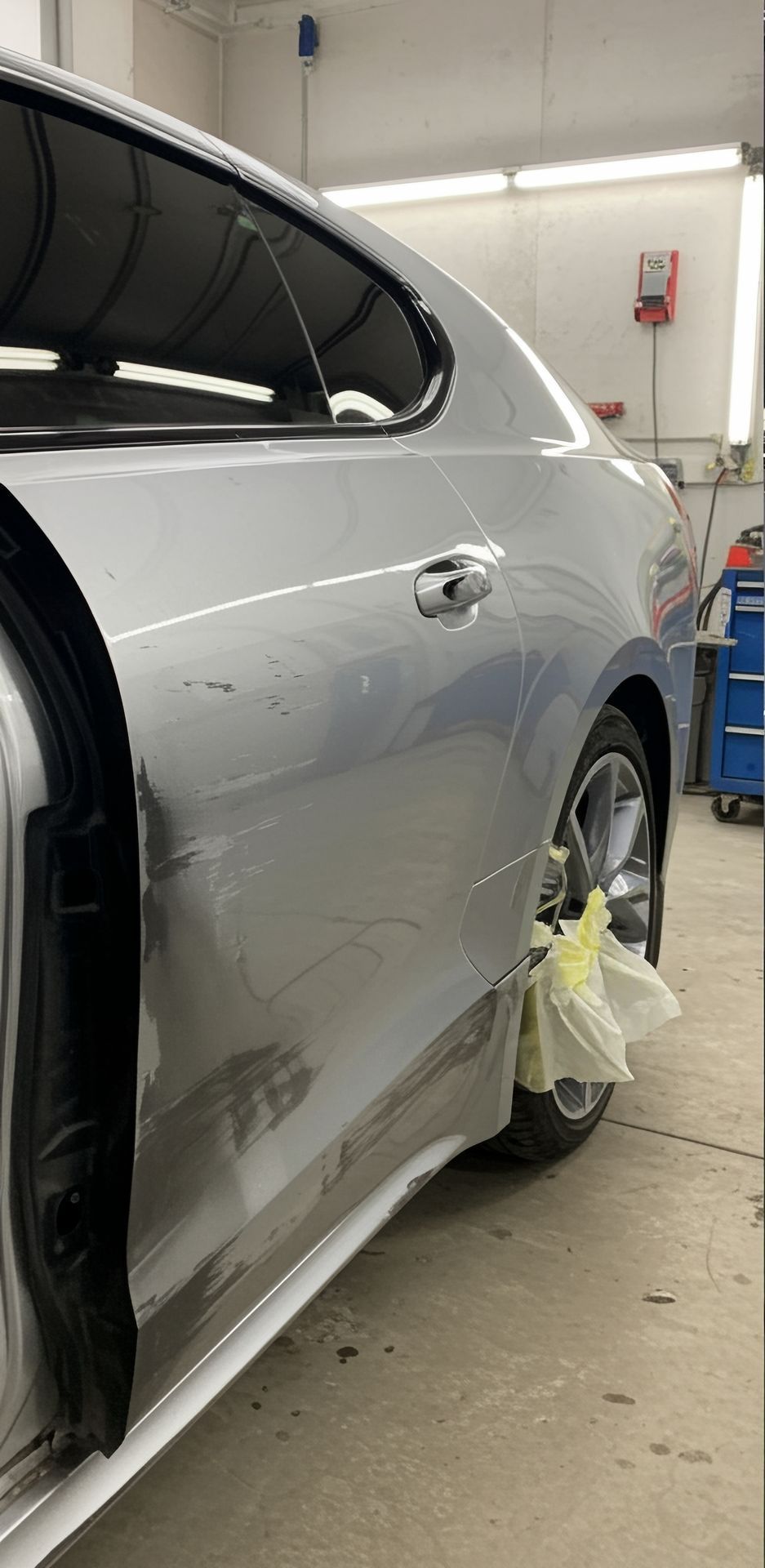 A silver car is sitting in a garage with the door open.
