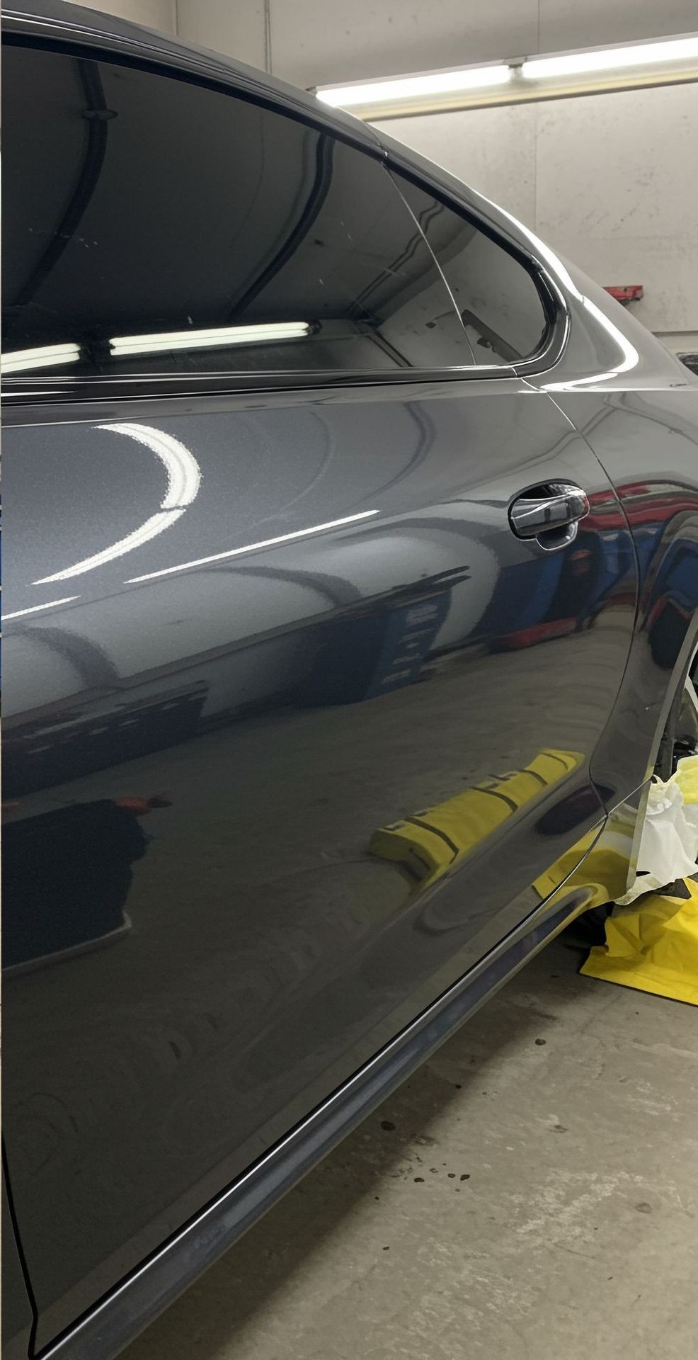 A gray car is parked in a garage next to a yellow curb.