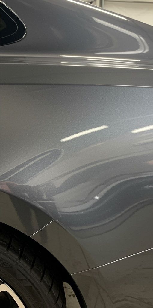 A close up of the side of a gray car in a garage.