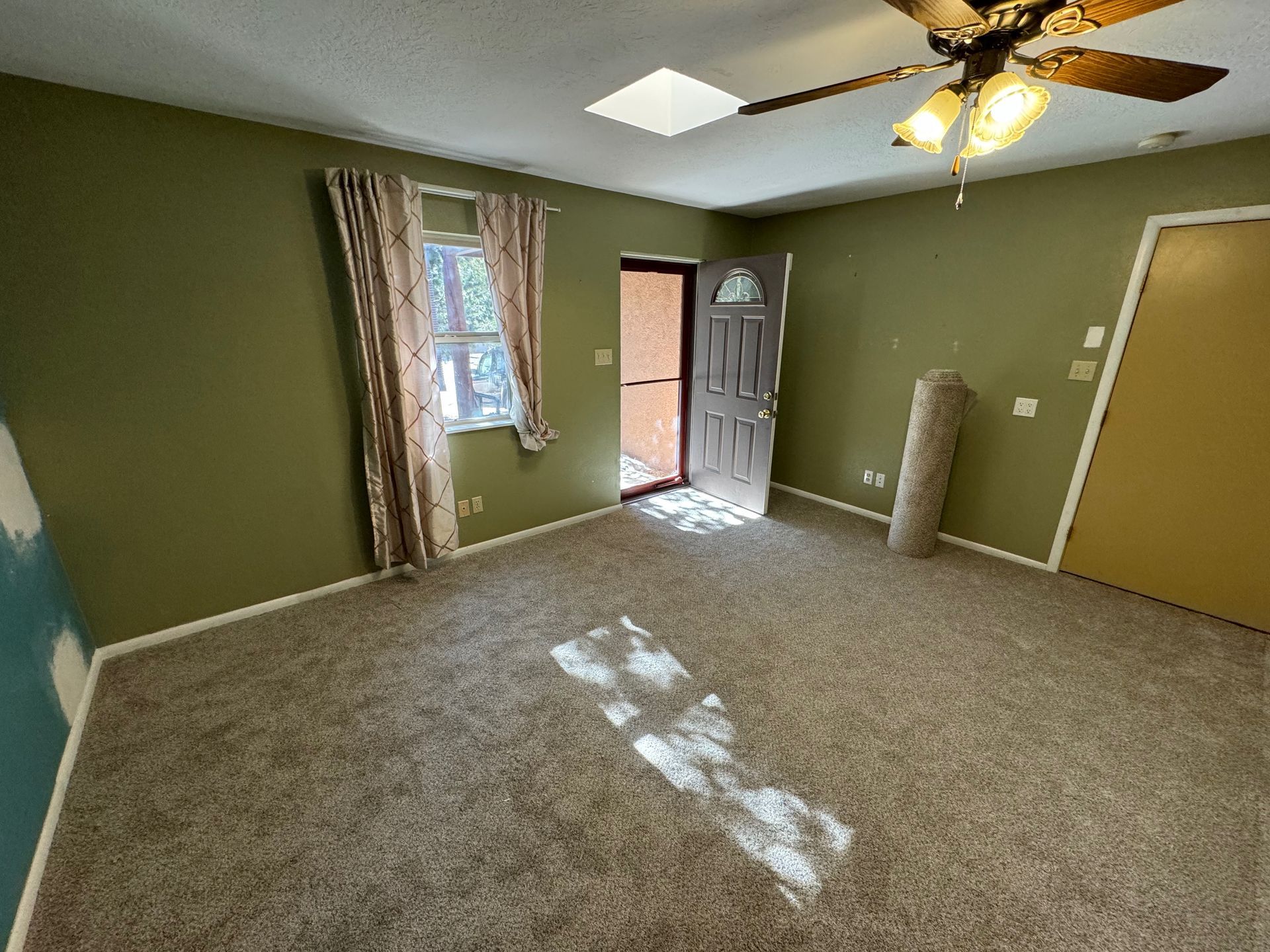 An empty living room with a ceiling fan and a door.