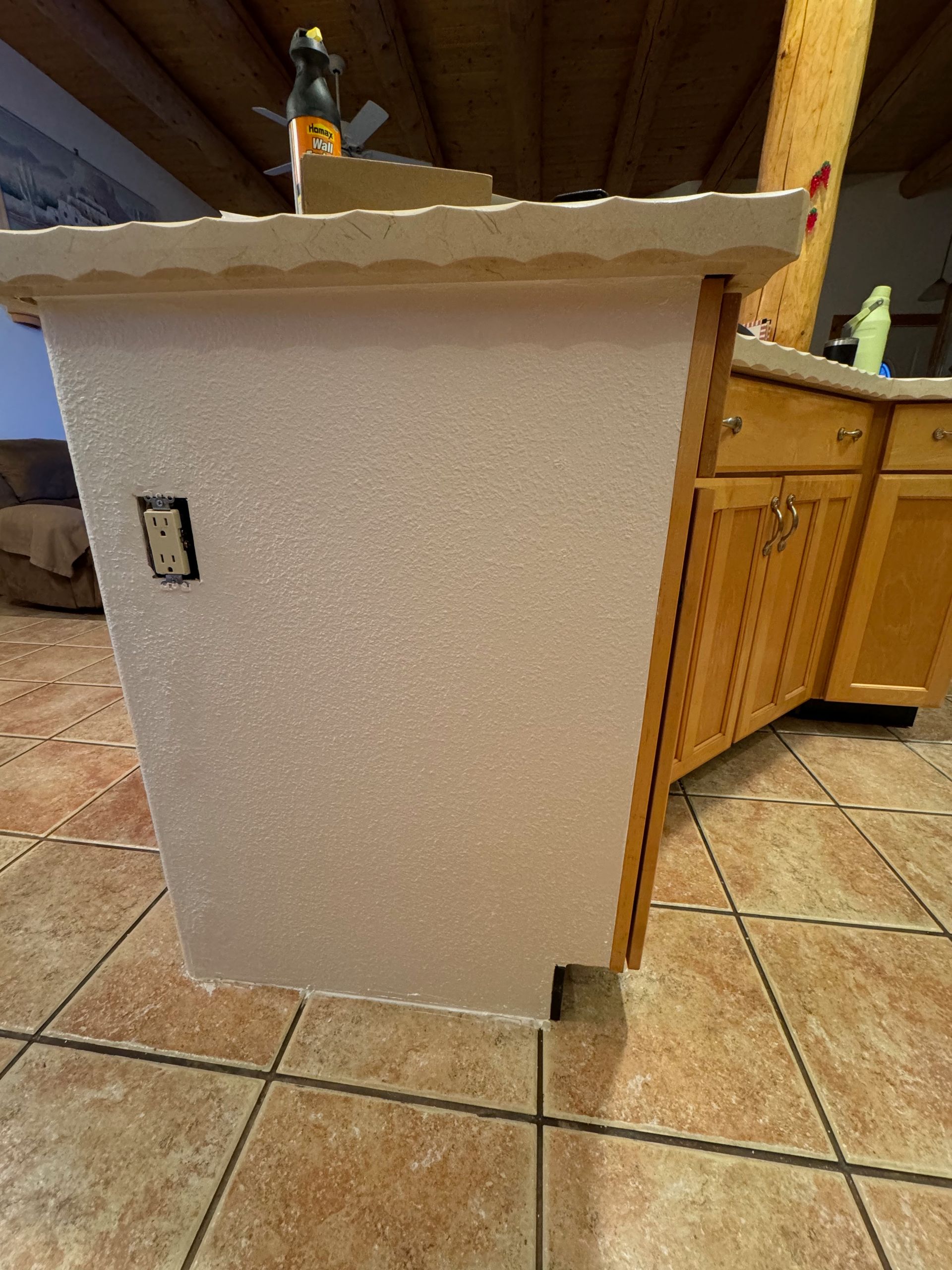 A white box is sitting on a tiled floor next to a wooden cabinet.