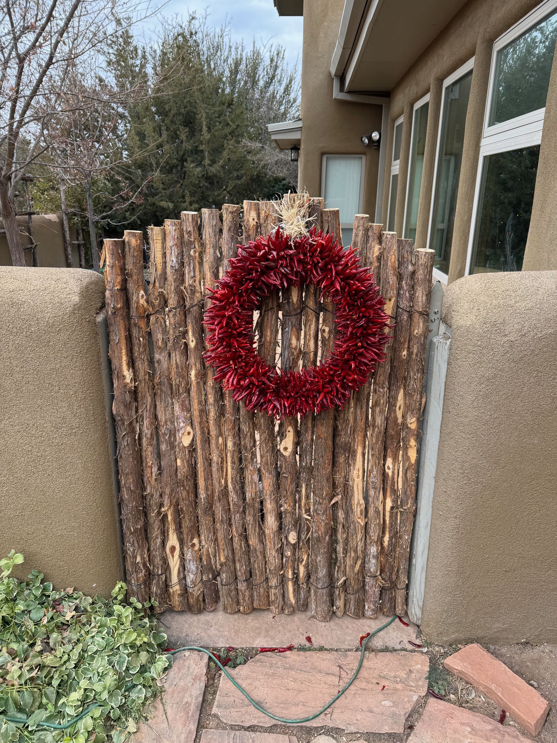 A wooden gate with a red wreath hanging on it.