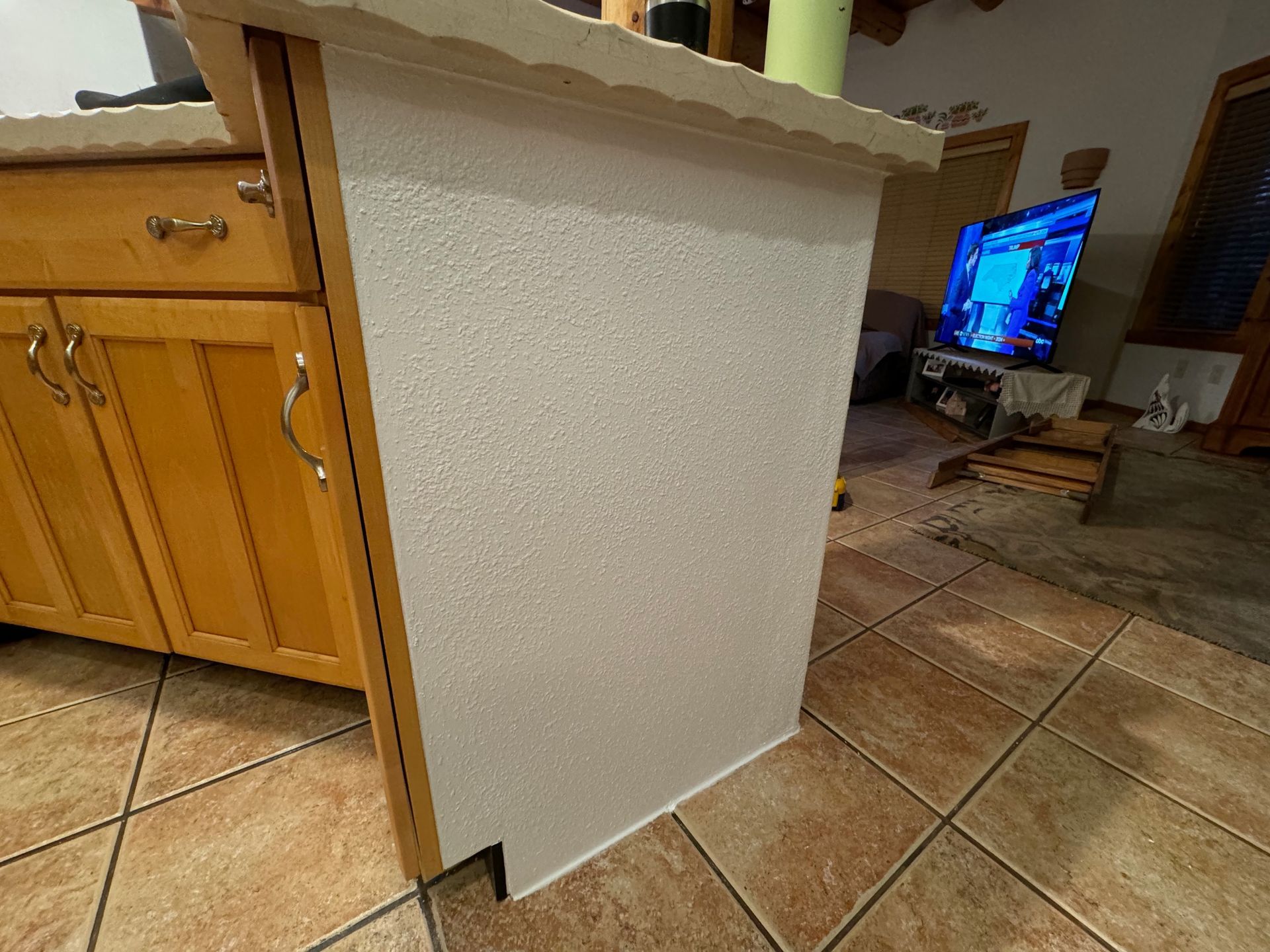 A kitchen with a white counter top and a tv on the counter.