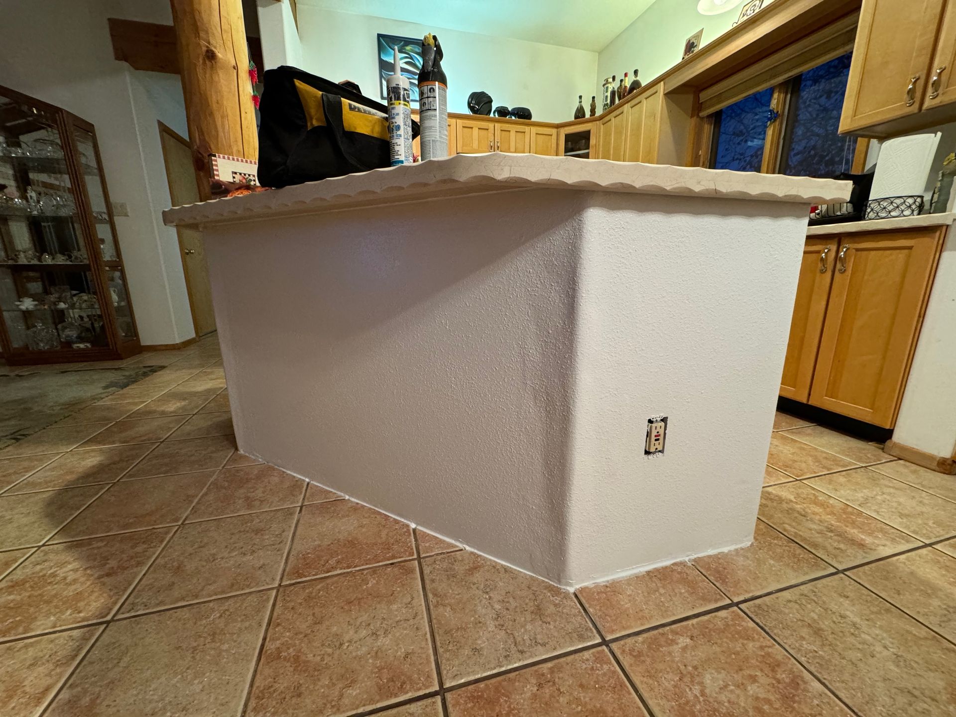 A large white box is sitting on top of a tiled floor in a kitchen.