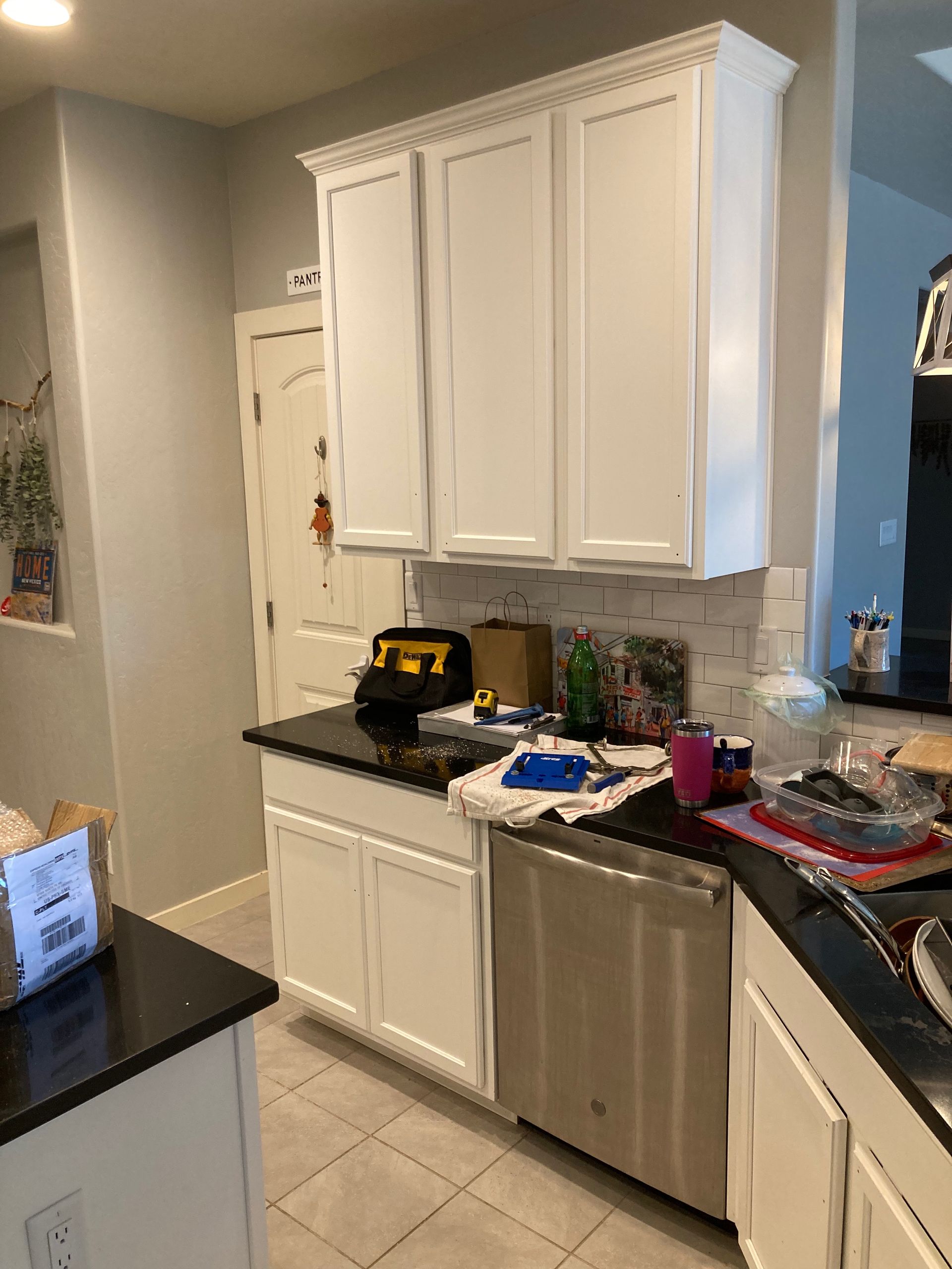 A kitchen with white cabinets and a stainless steel dishwasher.